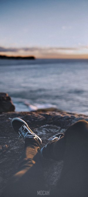 Person sitting by the sea at dusk