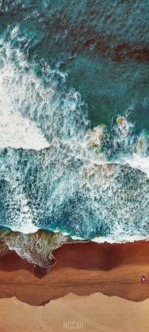 Aerial view of ocean waves crashing on a sandy beach