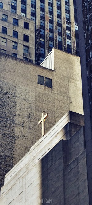 Cross on a church building among skyscrapers