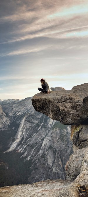Woman sitting on a rock ledge overlooking mountains