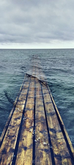 Wooden pier extending into the sea under a cloudy sky