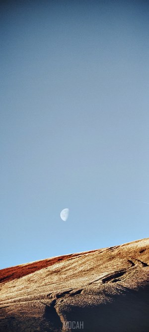 Half moon over a rocky landscape