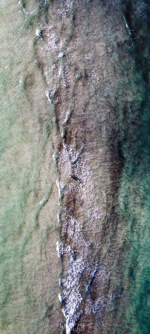 Aerial view of shallow ocean water with waves and sand ripples