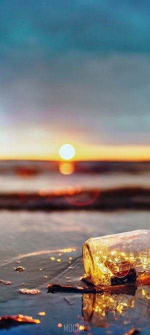 Fairy lights in a mason jar on a beach at sunset