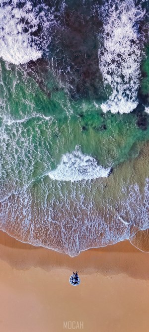 Aerial view of person on inflatable tube on beach near waves