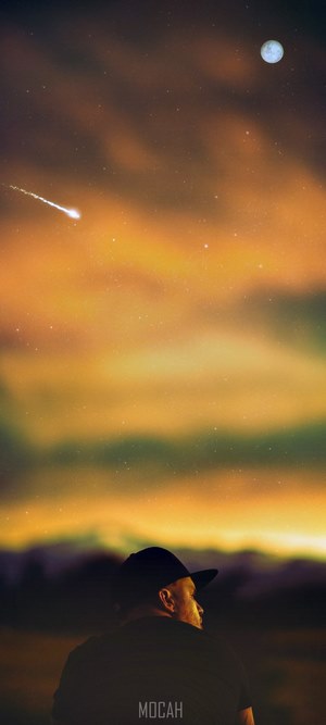Man watches meteor and moon in orange sky