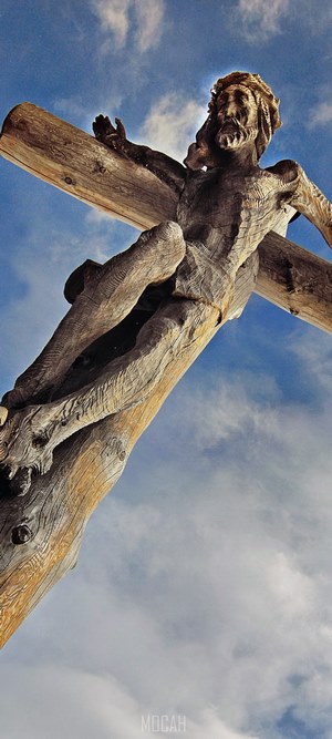 Wooden Jesus sculpture on a cross against the sky