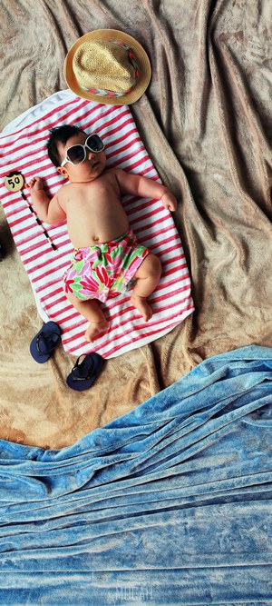 Baby on a beach towel with sunglasses and hat