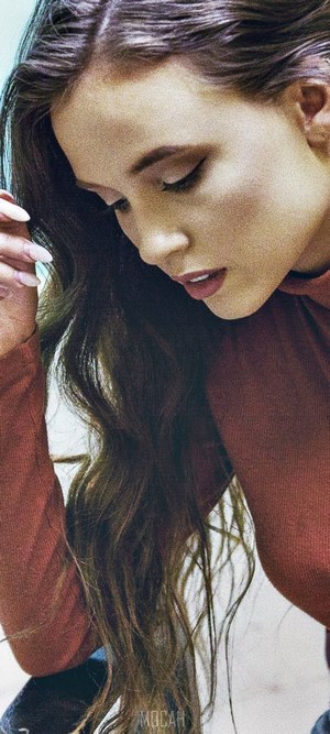Woman with long brown hair wearing a rust-colored top