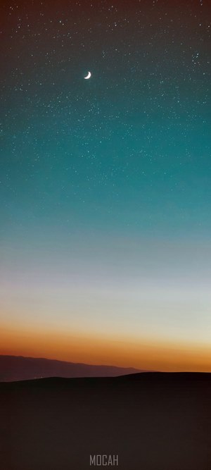Crescent moon in a starry night sky over mountains