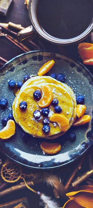 Pancakes with blueberries and orange slices on a plate