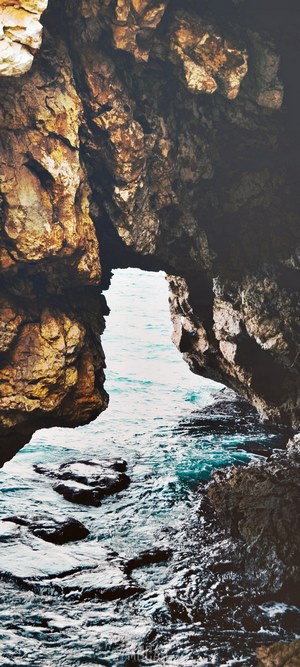 Ocean waves crashing through a rock archway