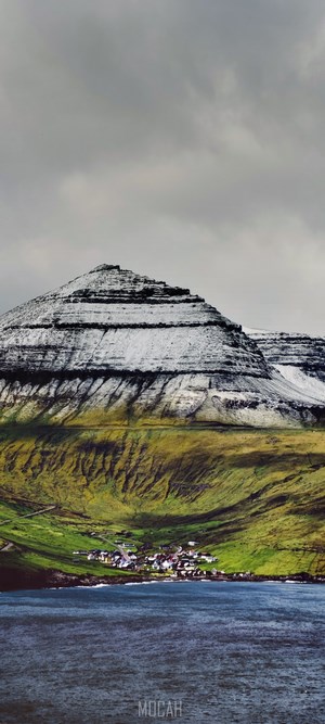 Snow-capped mountain overlooking a village by the sea