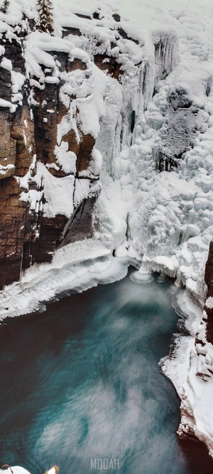 Frozen waterfall and river between snowy cliffs