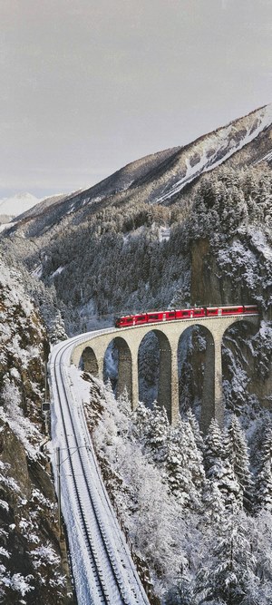 Red train on a snowy viaduct in the mountains