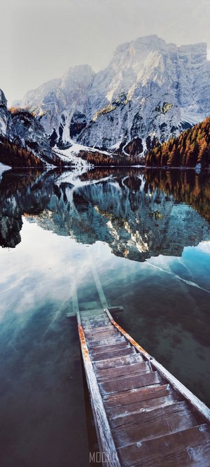 Wooden stairs leading into a calm lake with mountains reflected