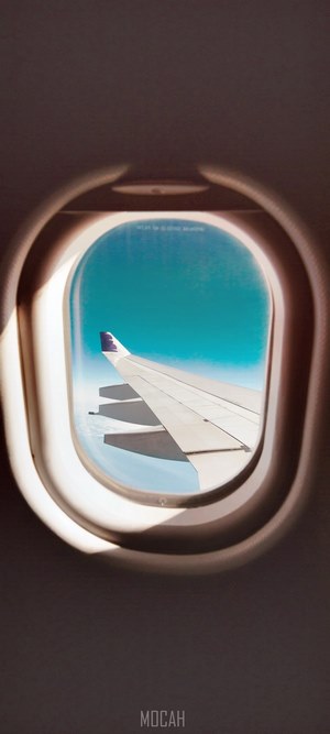 Airplane window view of wing and sky