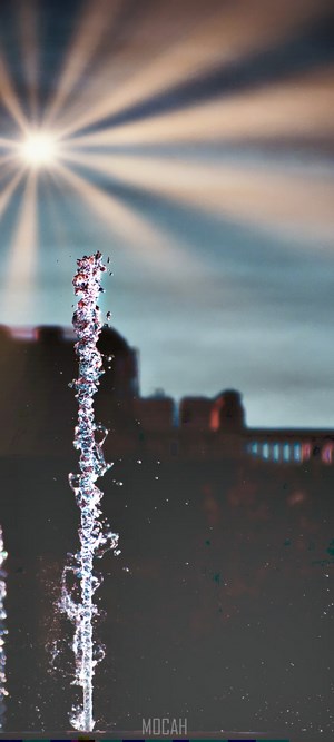 Fountain water stream with sunburst and buildings