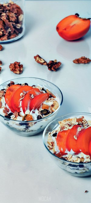Two bowls of yogurt parfait with persimmon and nuts