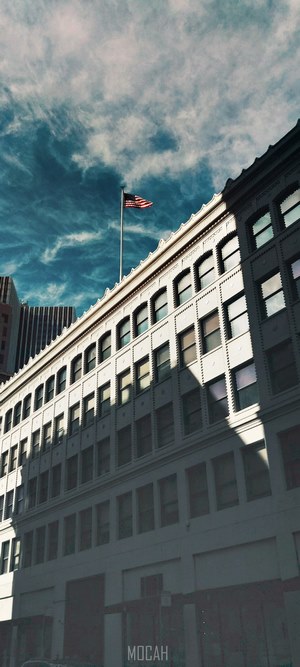 American flag on building facade with dramatic clouds