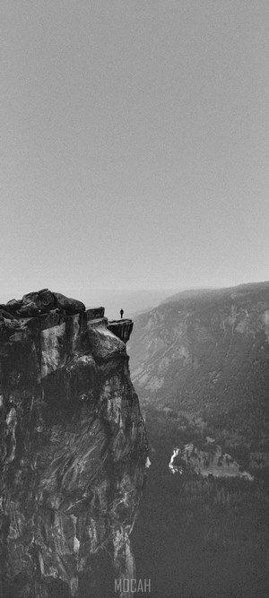 Person standing on a cliff edge overlooking a valley