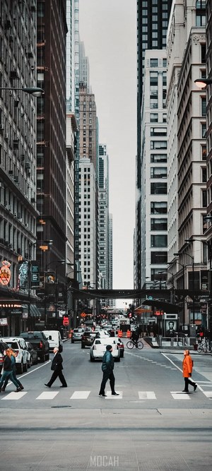 People crossing a busy city street with skyscrapers