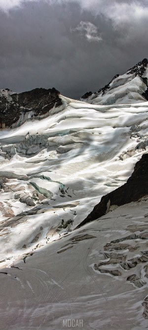 Snowy mountain slope under dark cloudy sky