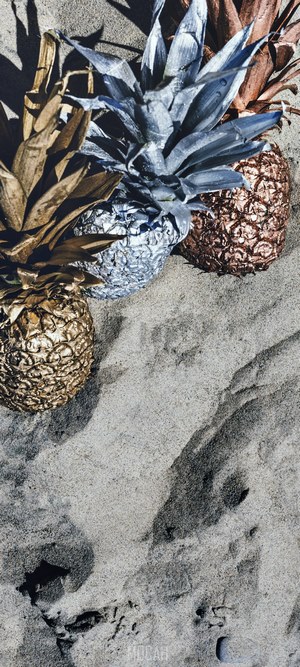 Three painted pineapples on sand