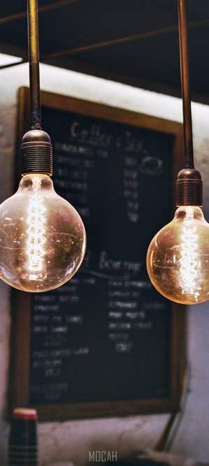 Edison bulbs hanging in front of a chalkboard menu