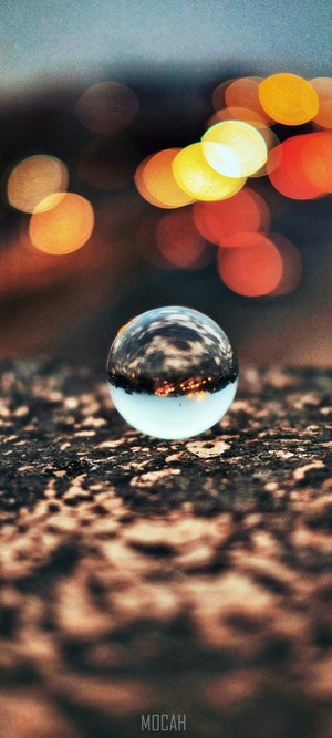 Glass sphere reflecting city lights on textured surface