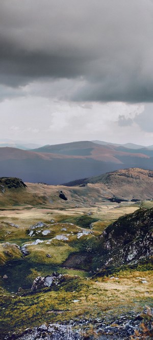 Mountainous landscape with rolling hills and cloudy sky