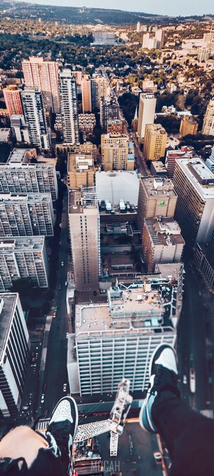 Aerial view of city buildings with person's feet in foreground