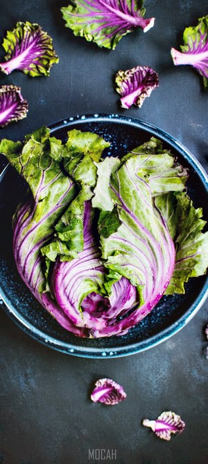 Purple kale in a bowl on a dark surface