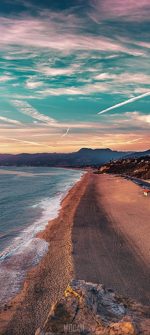 Beach and ocean at sunset with mountains