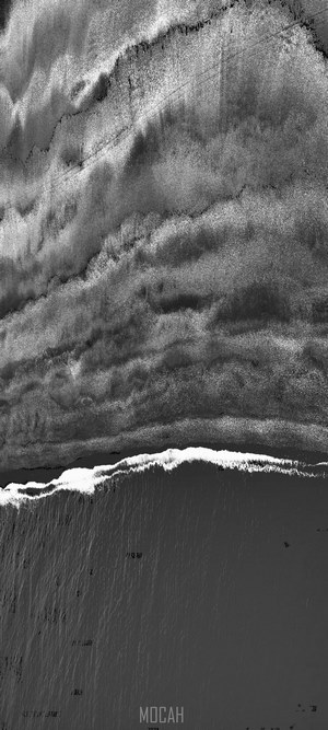 Black and white drone shot of shoreline with tide waves