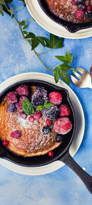 Dutch baby pancake with berries in cast iron skillet