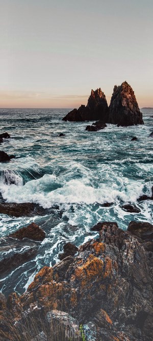 Rocky coastline with waves crashing at sunset