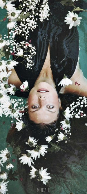Woman floating in water with white flowers