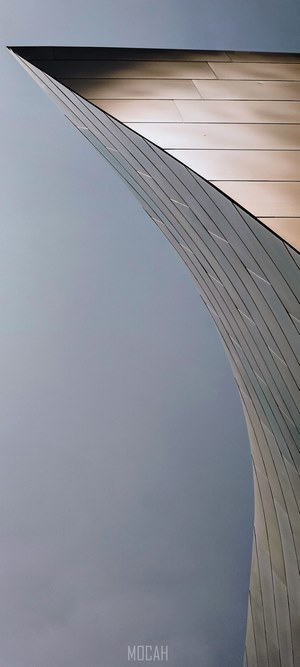 Modern architecture with curved metallic facade against sky