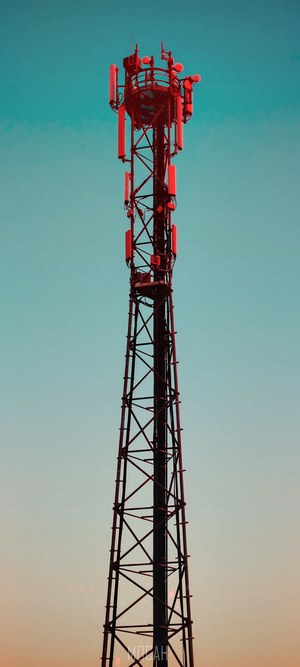 Telecom tower with red antennas against a gradient sky