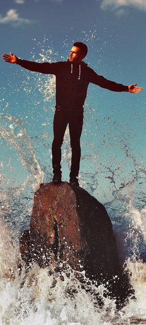 Man standing on rock in ocean waves