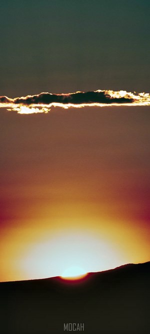 Sunset over a dark landscape with a cloud