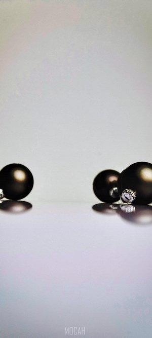 Four dark Christmas ornaments on a reflective surface