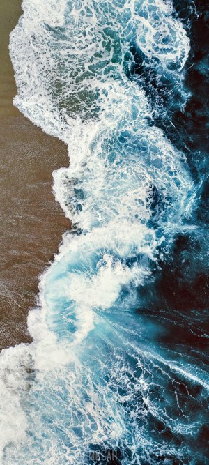 Aerial view of ocean waves crashing on a sandy beach