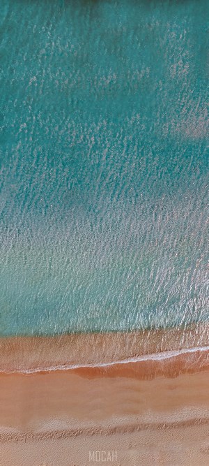 Aerial view of turquoise ocean waves meeting a sandy beach