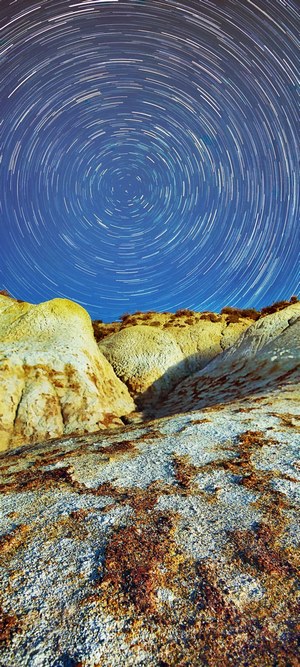 Star trails over desert rock formations at night