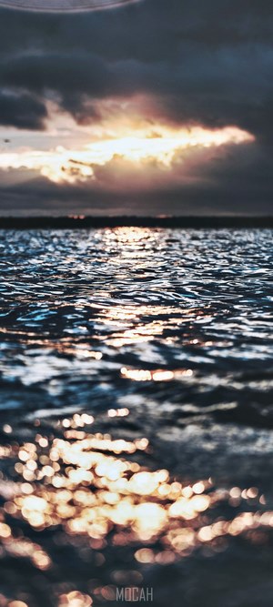 Sunset over water with dark clouds