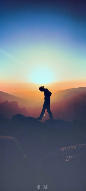 Silhouette of a person walking on a mountain at sunset