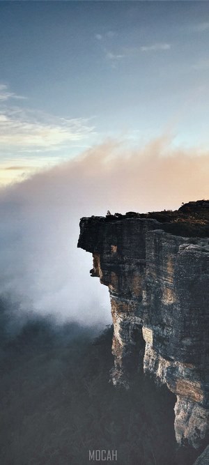 Person on cliff edge overlooking foggy valley
