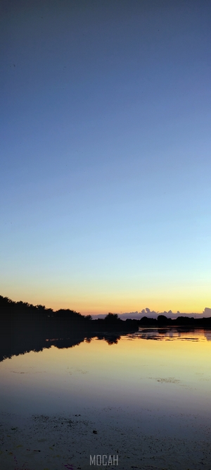 Sunset over a calm lake with tree reflections